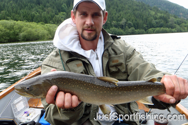 Photo of fisherman in a boat holding a bull trout.