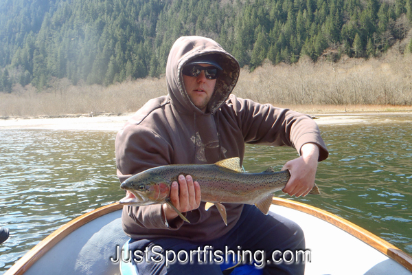 Fisherman in a boat holding a rainbow trout.