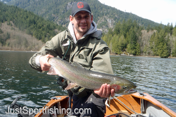 Fisherman in a boat holding a rainbow trout.