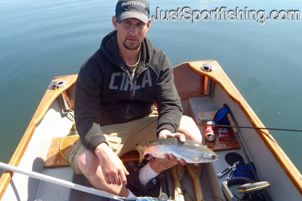 Fisherman in boat holding a rainbow trout.