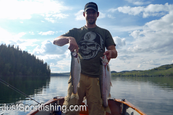 Two rainbow trout being held by fisherman.