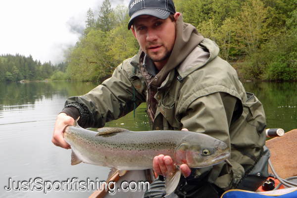 Fisherman on lake holding a big rainbow trout.