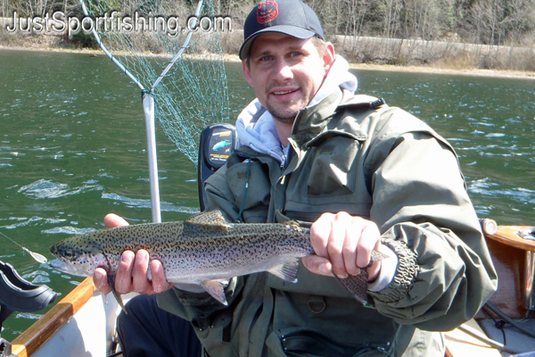 Fisherman holding a steelhead trout in a boat.